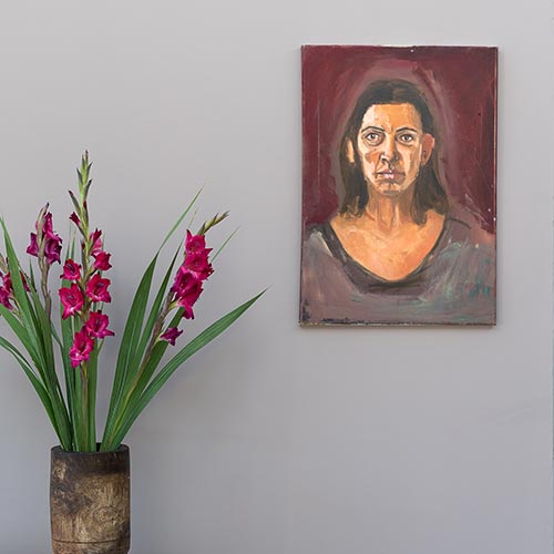 Vase with flowers and portrait painting on light brown wall