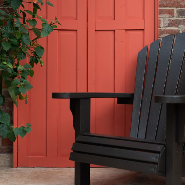 Black garden chair in front of red painted door