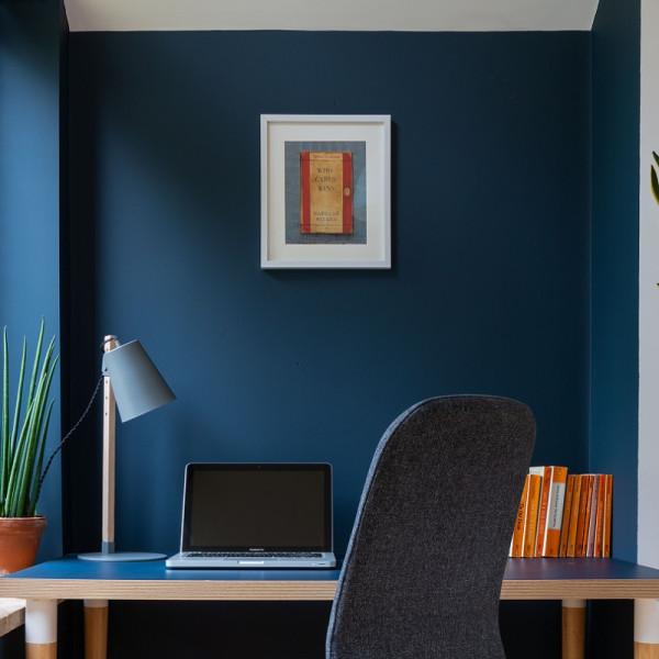 Office chair and desk with laptop, lamp and books in front of Smoke Blue coloured wall