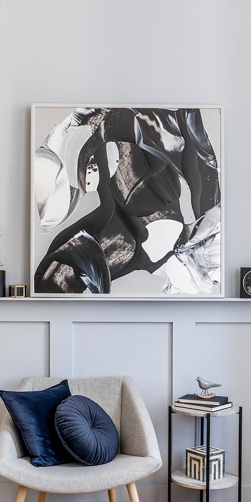 Light grey painted wall with picture, armchair and cushions